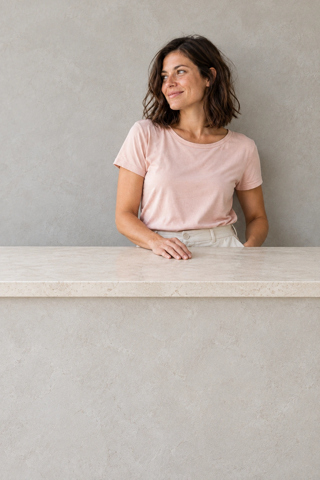 Frau im rosafarbenen Shirt an einer hellen Steinwand