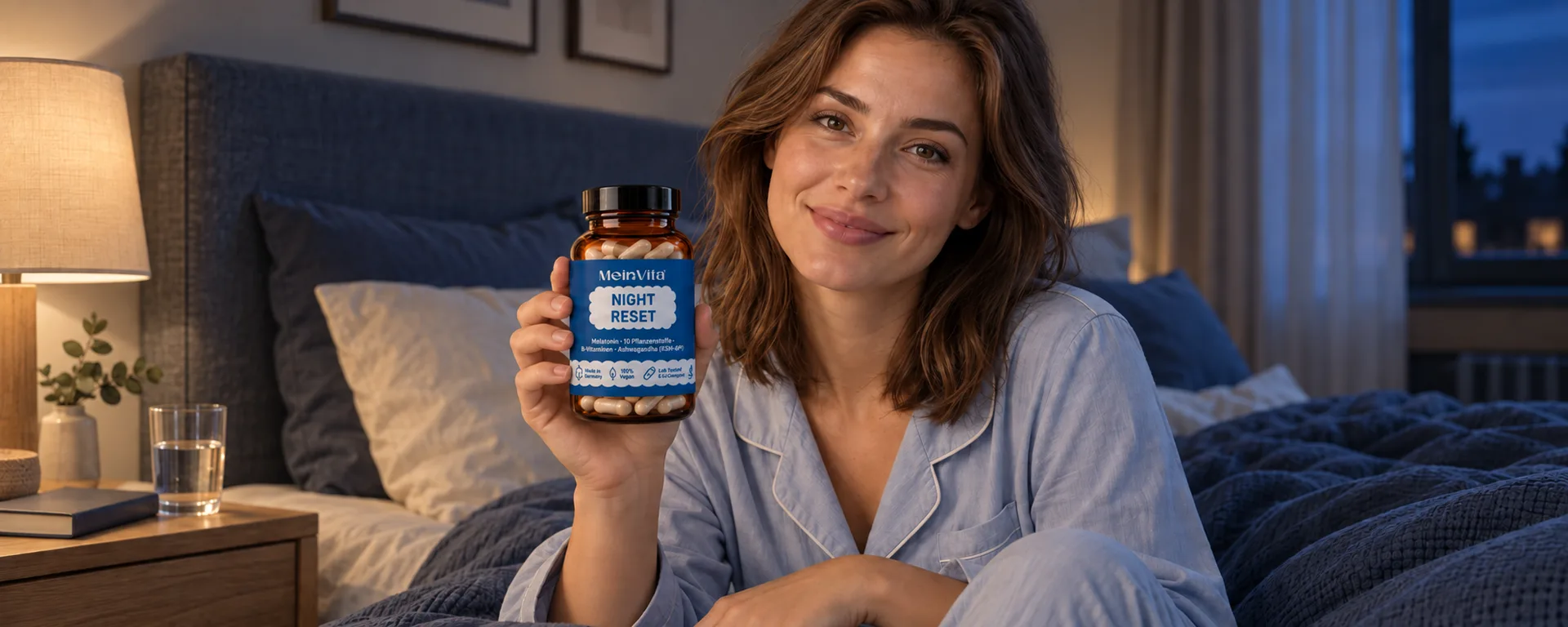Eine lächelnde Frau hält abends im Schlafzimmer eine MeinVita Night Reset Flasche in die Höhe
